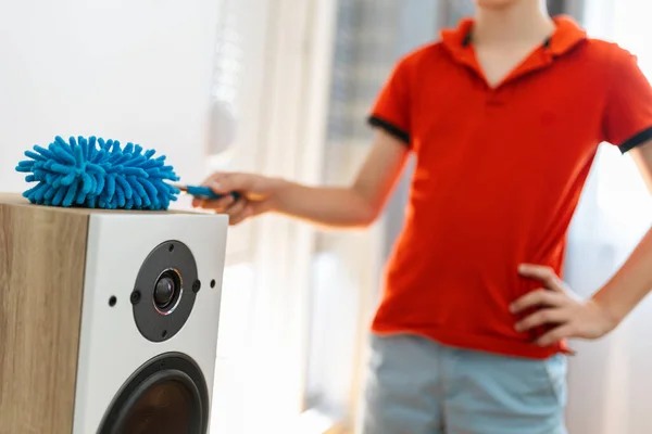 Male child cleaning the speakers . Doing his chore