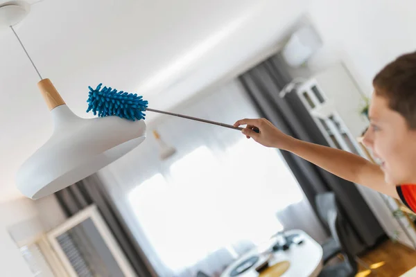 Männliches Kind Beim Putzen Des Kronleuchters Seine Hausarbeit Erledigen — Stockfoto