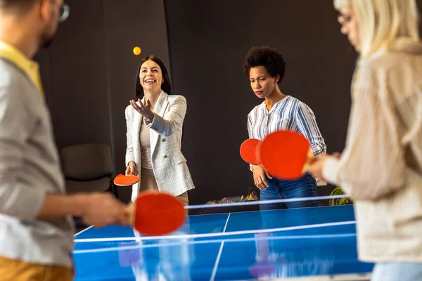 Young people playing table tennis in the office at work