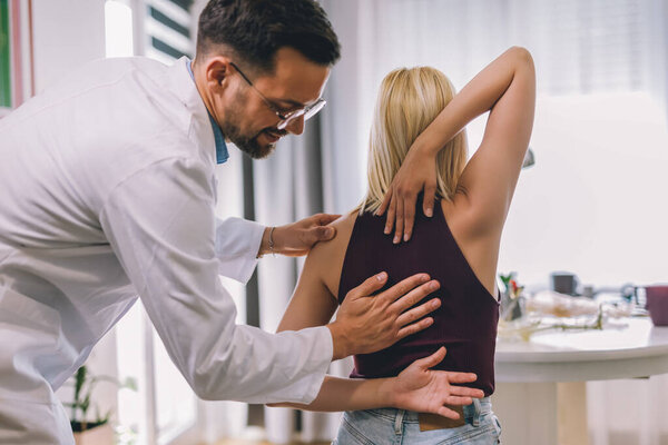 Хиропрактик лечит молодую женщину как пациента в своем кабинете.