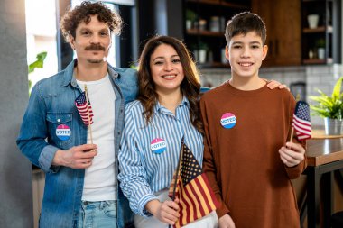 Latino family voted in the elections. Holding American flag. clipart