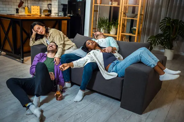 Party multiracial friends, drunk and hungover sleeping on a sofa in the living room after the party.