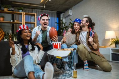 Amerikan bayraklarıyla ragbi izleyen çok ırklı bir arkadaş grubu..