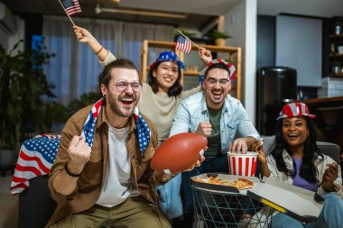 Amerikan bayraklarıyla ragbi izleyen çok ırklı bir arkadaş grubu..