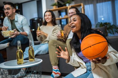 Basketbol maçı izleyen, bira içen ve tezahürat yapan çok ırklı bir arkadaş grubu..