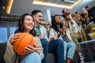 Basketbol maçı izleyen, bira içen ve tezahürat yapan çok ırklı bir arkadaş grubu..