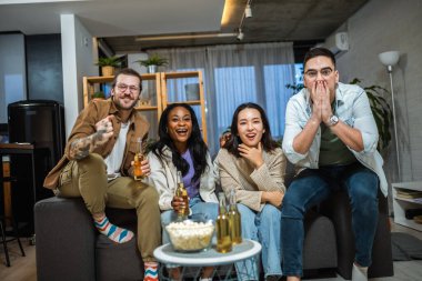 Oyun izleyen, tezahürat yapan ve bira içen çok ırklı bir arkadaş grubu..