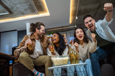 Oyun izleyen, tezahürat yapan ve bira içen çok ırklı bir arkadaş grubu..