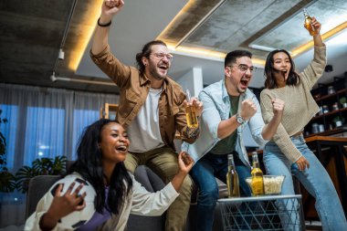 Futbol maçı izleyen, tezahürat yapan ve bira içen çok ırklı arkadaş grubu..
