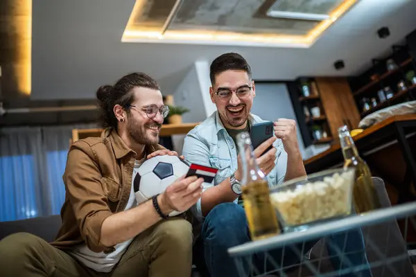 Two friends online betting on soccer with their credit card.