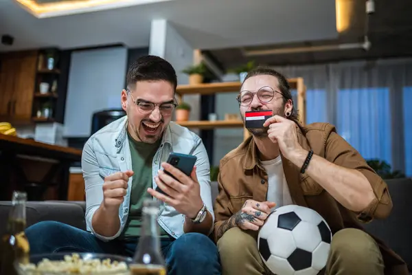 Two friends online betting on soccer with their credit card.