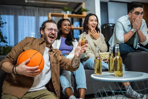 Basketbol maçı izleyen, bira içen ve tezahürat yapan çok ırklı bir arkadaş grubu..