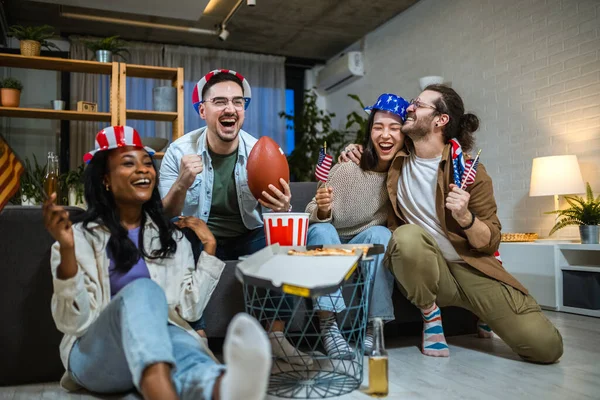 Amerikan bayraklarıyla ragbi izleyen çok ırklı bir arkadaş grubu..
