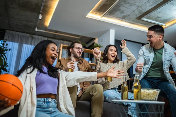 Basketbol maçı izleyen, bira içen ve tezahürat yapan çok ırklı bir arkadaş grubu..