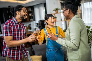 Evde bira içip pizza yiyen çok ırklı bir arkadaş grubu..