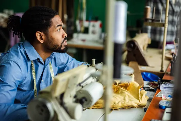 stock image Young male African American tailor sew with a sewing machine in his own atelier