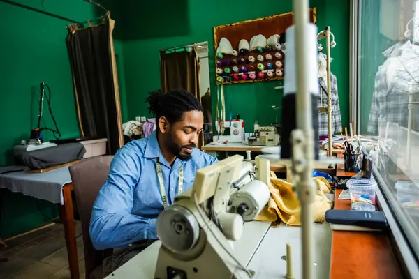 stock image Young male African American tailor sew with a sewing machine in his own atelier