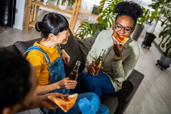 Evde bira içip pizza yiyen çok ırklı bir arkadaş grubu..