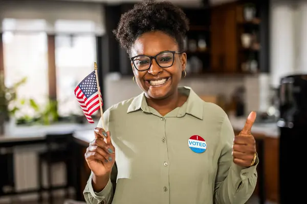 African American woman standing with an American flag after voting.