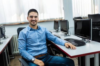 Bilgisayar laboratuvarında masaüstü bilgisayarı kullanan erkek öğrenci.