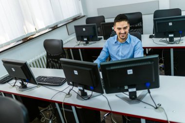 Bilgisayar laboratuvarında masaüstü bilgisayarı kullanan erkek öğrenci.