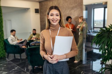 Sıradan giyinmiş bir iş kadını bir ofis binasının lobisinde bir iş adamının önünde duruyor.