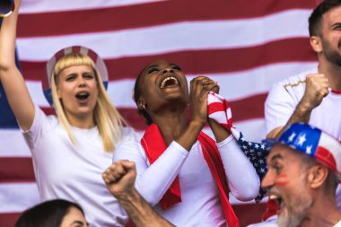Amerikan futbolu ve futbol taraftarları stadyumda bayraklar ve diğer ekipmanlarla tezahürat yapıyorlar