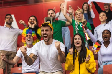 Alman futbol / futbol taraftarları stadyumda bayraklar ve diğer ekipmanlarla tezahürat yapıyorlar