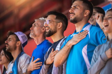 Futbol taraftarları stadyumda marş söylüyorlar.