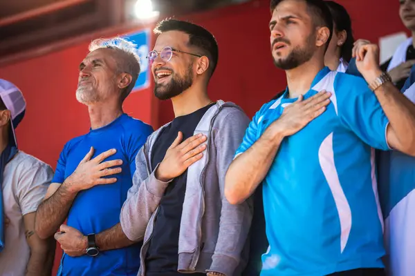 Futbol taraftarları stadyumda marş söylüyorlar.