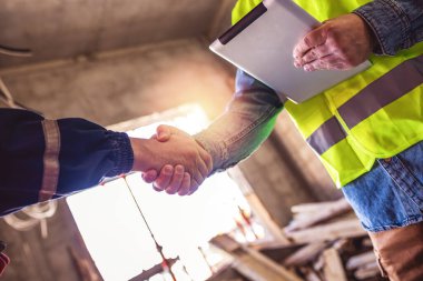 Müteahhit. İnşaat işçisi takımı inşaat şantiyesi, müteahhit, mühendislik, ortaklık, inşaat konseptinde proje sözleşmesi üzerine el sıkışıyor