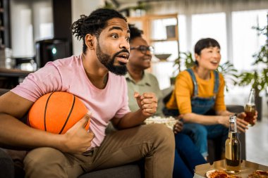 Basketbol maçı izleyen, pizza yiyen, bira içen ve tezahürat yapan çok ırklı bir arkadaş grubu..