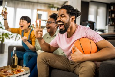 Basketbol maçı izleyen, pizza yiyen, bira içen ve tezahürat yapan çok ırklı bir arkadaş grubu..