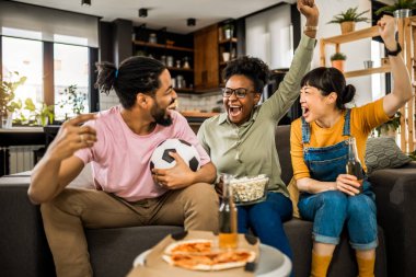Futbol maçı izleyen, tezahürat yapan, pizza yiyen ve bira içen çok ırklı bir arkadaş grubu..