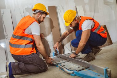 İnşaat alanında Tilers, işçi inşaat sırasında büyük bir döşeme kiremit kesiyor, döşeme kesme ekipmanları..