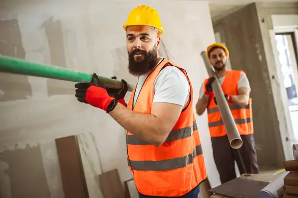 Dva Stavební Dělníci Nesoucí Potrubí Staveništi Pracovní Koncepce — Stock fotografie