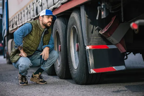 stock image Young handsome truck driver checking if everything is good with his truck.