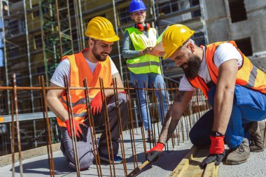 İnşaat alanında çalışan üç inşaat işçisi..