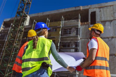 İnşaat ekibi inşaat alanında mimari yenilikler için işbirliği içeren bir proje planlıyor. Mimari, tasarım ve mühendisler başarılı olmak için takım çalışmasına sahipler.