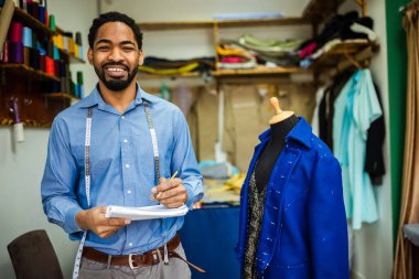 Afrikalı Amerikalı erkek moda tasarımcısı, terzi yeni tasarımı için çizim yapıyor.