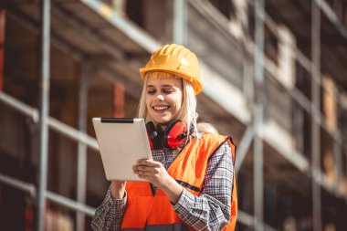 Tablet kullanan mimar kadın sanayide inşaat alanında mutlu, planlama ve teftiş.