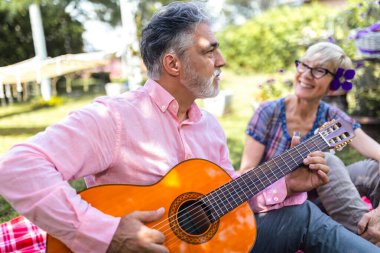 Parkta gitarlı, olgun bir çift.