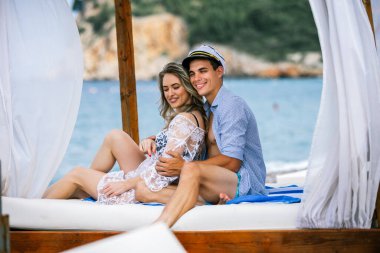 Genç ve güzel bir çift sahilde iyi vakit geçiriyor. Erkek arkadaşı denizci şapkası takıyor..