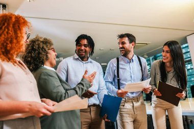 Çok ırklı bir grup iş arkadaşı koridorda yürüyor ve iş hakkında konuşuyorlar.. 