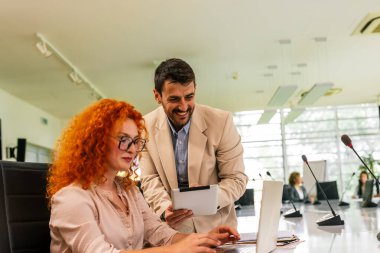 Modern ofiste bilgisayarlarında ve tabletlerinde birlikte çalışan iki iş ortağı..