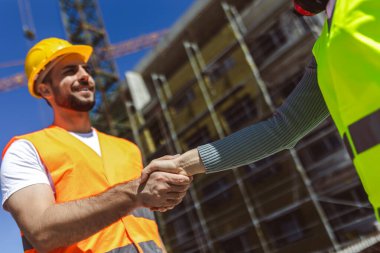 Müteahhit. İnşaat işçisi takımı inşaat şantiyesi, müteahhit, mühendislik, ortaklık, inşaat konseptinde proje sözleşmesi üzerine el sıkışıyor