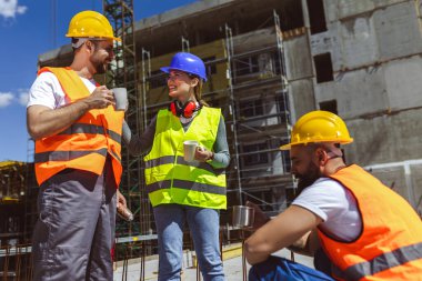 İnşaat alanında kahve ve öğle yemeği arası veren üç inşaat işçisi..