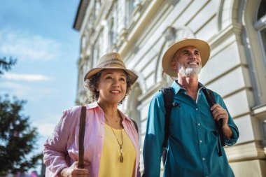 Yeni şehri keşfeden yaşlı evli bir çift. Şapka ve sırt çantası takıyorlar..