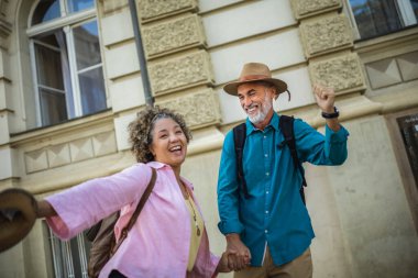 Şehir merkezinde mutlu mesut ayakta duran yaşlı evli bir çift. Havaya şapka atmak..