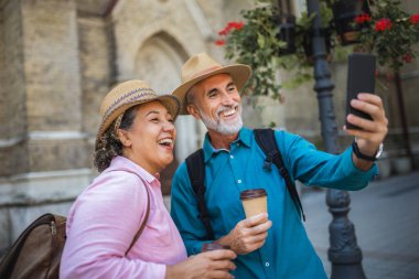 Yaşlı evli bir çift kahve molasındayken selfie çekiyor. Yeni şehri keşfeden turistler.